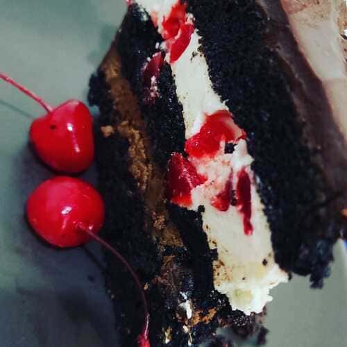 rebanada de pastel Diablo, bizcocho de chocolate húmedo, con rellenos de chocolate blanco y cerezas, y chocolate semiamargo